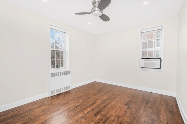 spare room with dark wood-type flooring, ceiling fan, cooling unit, and radiator heating unit