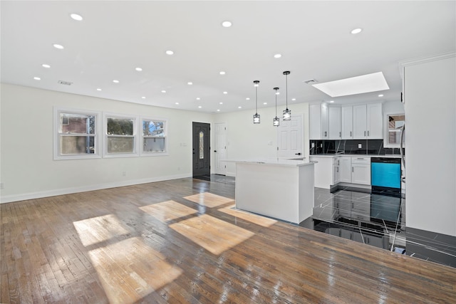 kitchen featuring dishwashing machine, pendant lighting, white cabinets, a center island, and a skylight