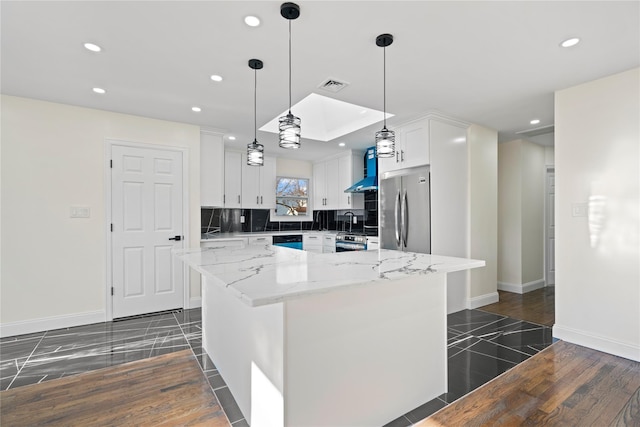 kitchen with a center island, decorative backsplash, light stone countertops, white cabinets, and stainless steel fridge