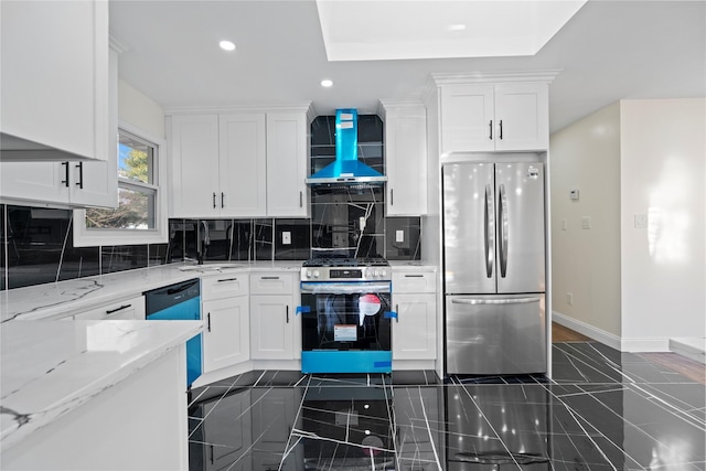 kitchen featuring white cabinetry, light stone countertops, wall chimney range hood, and stainless steel appliances