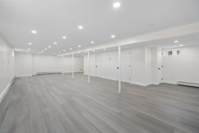 basement with light hardwood / wood-style flooring and a baseboard radiator