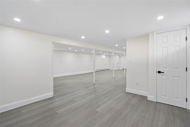 basement featuring a baseboard radiator and light wood-type flooring