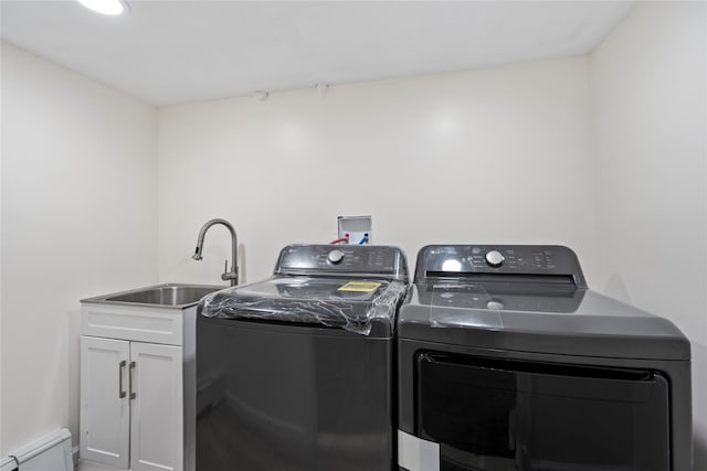 laundry area with cabinets, sink, a baseboard heating unit, and washing machine and dryer