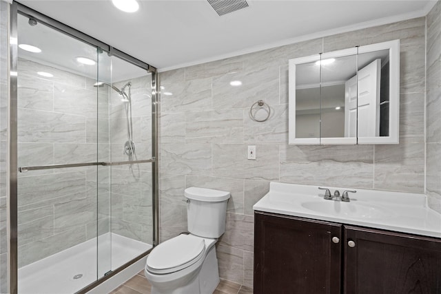 bathroom with toilet, vanity, tile walls, and walk in shower