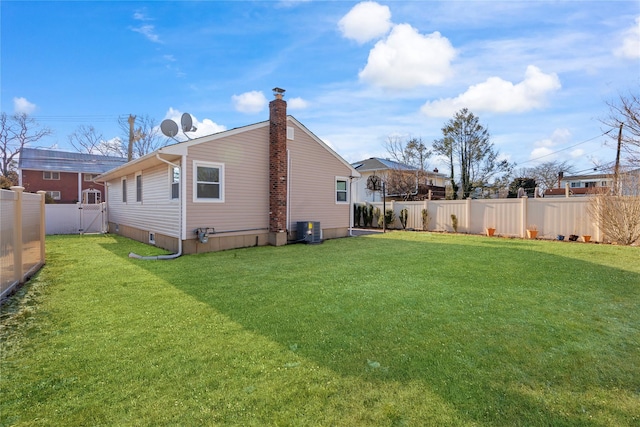 back of house with central AC unit and a yard