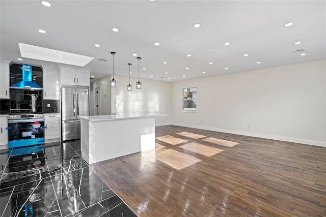 kitchen with wall chimney range hood, a kitchen island, white cabinetry, hanging light fixtures, and stainless steel appliances