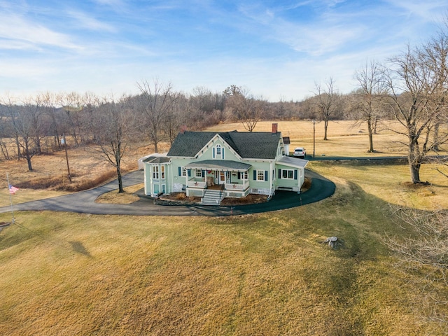 view of front facade with covered porch, a rural view, and a front lawn