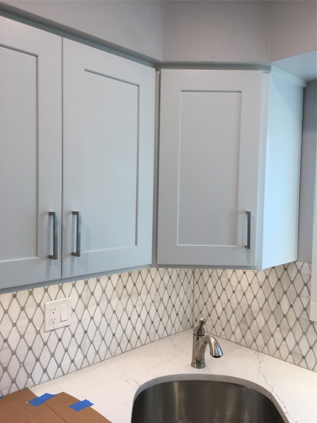 details with light stone countertops, white cabinets, tasteful backsplash, and sink