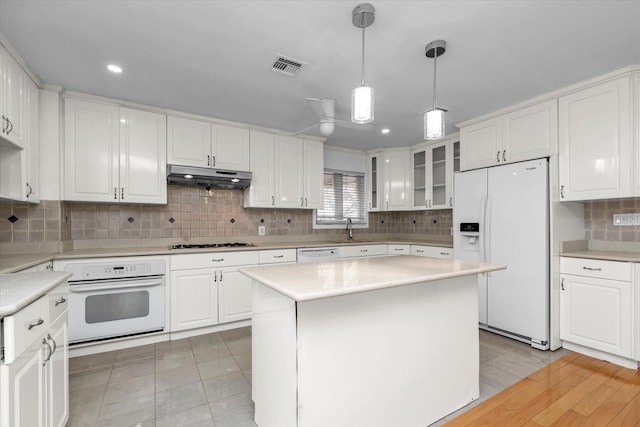 kitchen featuring pendant lighting, white appliances, white cabinets, a center island, and light tile patterned flooring