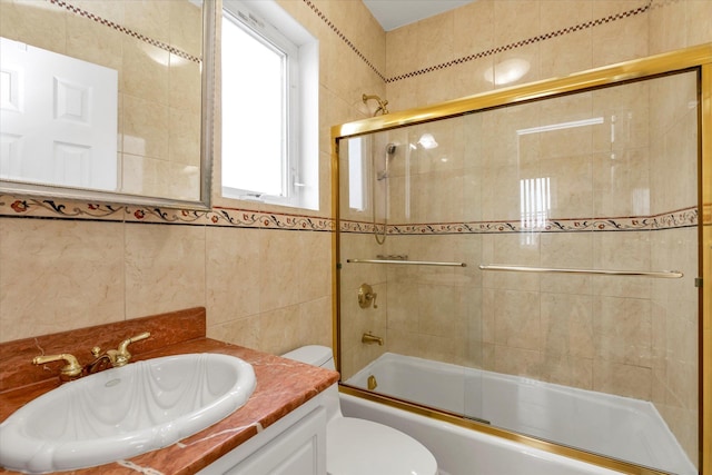 full bathroom featuring vanity, toilet, enclosed tub / shower combo, and tile walls