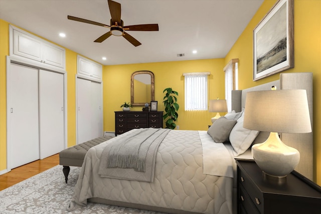 bedroom featuring multiple closets, ceiling fan, and light hardwood / wood-style floors