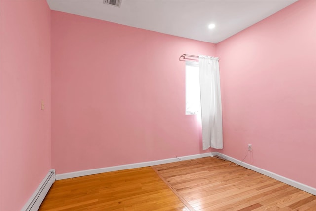 empty room featuring a baseboard radiator and light hardwood / wood-style flooring