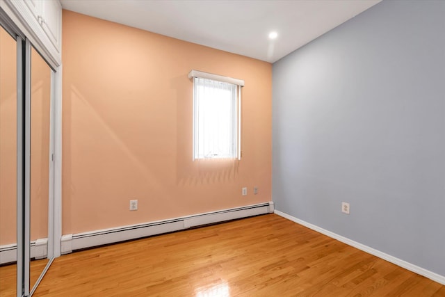 spare room featuring a baseboard radiator and light hardwood / wood-style flooring