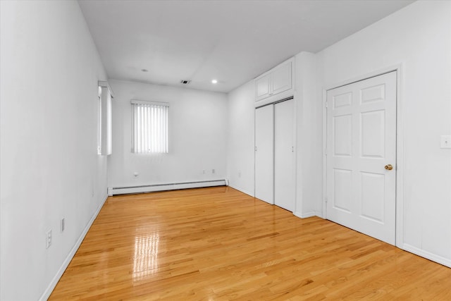 unfurnished bedroom featuring a baseboard radiator and light wood-type flooring