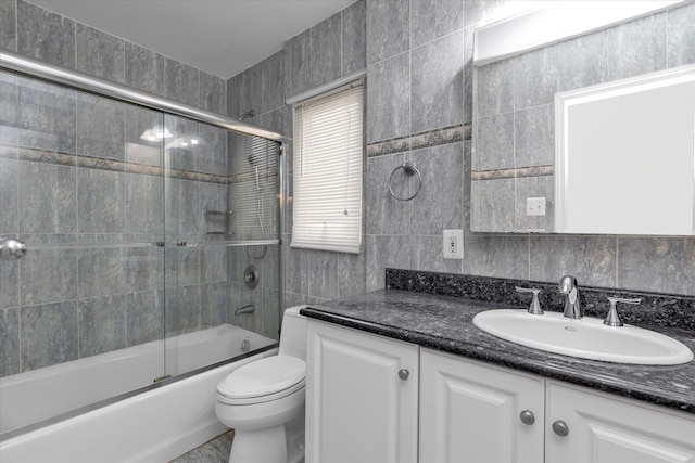 full bathroom with tile walls, shower / bath combination with glass door, and vanity