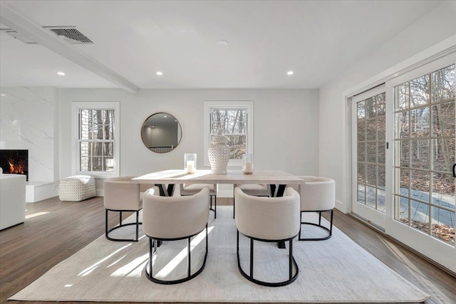 dining room with a premium fireplace, plenty of natural light, and wood-type flooring