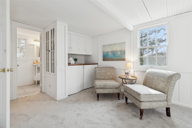 living area featuring light colored carpet and beam ceiling