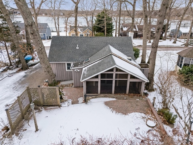 snow covered back of property featuring a sunroom