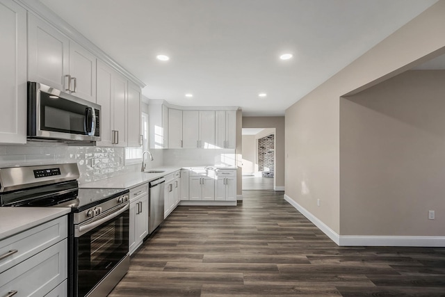 kitchen with decorative backsplash, sink, dark wood-type flooring, stainless steel appliances, and white cabinets