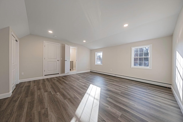 unfurnished room featuring dark wood-type flooring, a baseboard heating unit, and vaulted ceiling