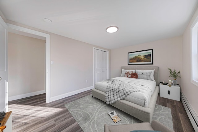 bedroom featuring baseboard heating, a closet, and wood-type flooring