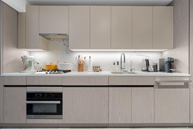 kitchen with appliances with stainless steel finishes, cream cabinetry, backsplash, and sink