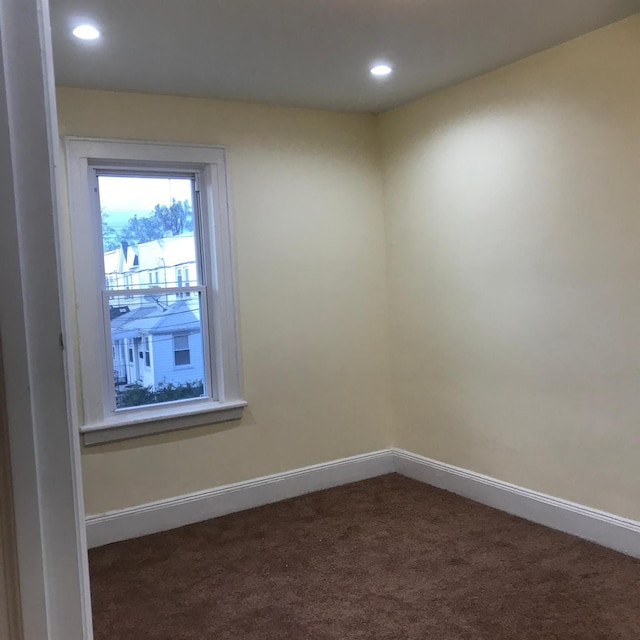 spare room with dark colored carpet