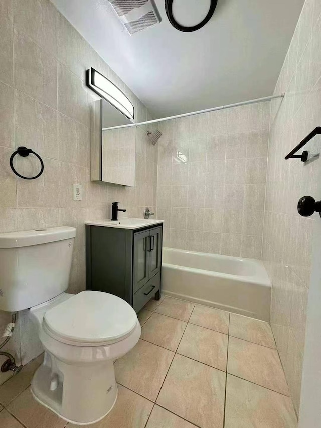 full bathroom with tile patterned flooring, toilet, vanity, tile walls, and tiled shower / bath