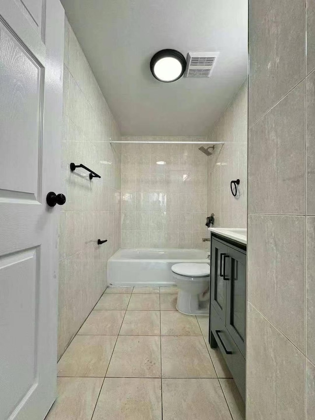 full bathroom with tile patterned floors, vanity, tile walls, and tiled shower / bath combo