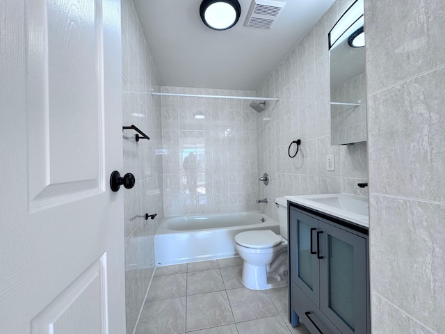 full bathroom featuring tile walls, tiled shower / bath combo, vanity, toilet, and tile patterned floors