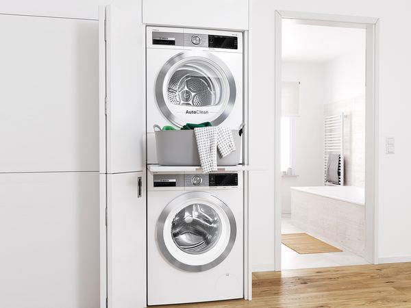 laundry area with stacked washing maching and dryer and light hardwood / wood-style floors