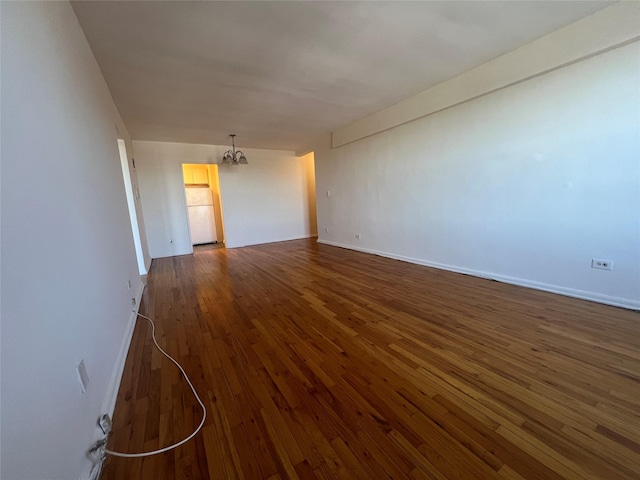 empty room featuring dark hardwood / wood-style floors and an inviting chandelier