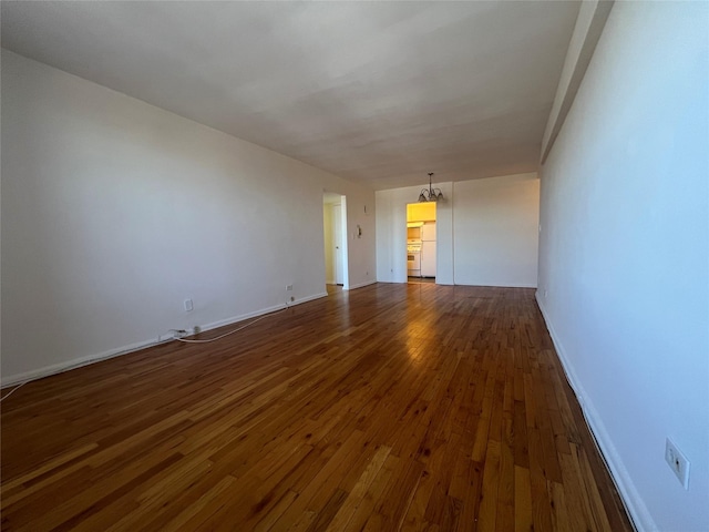 empty room with dark hardwood / wood-style floors and a chandelier