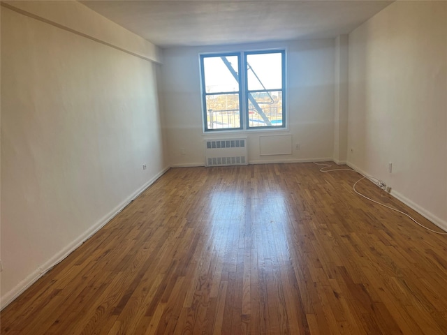 empty room featuring radiator heating unit and dark hardwood / wood-style flooring