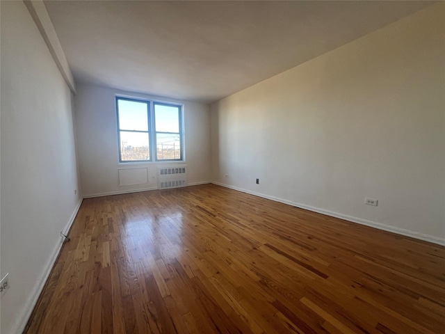 empty room featuring radiator and wood-type flooring