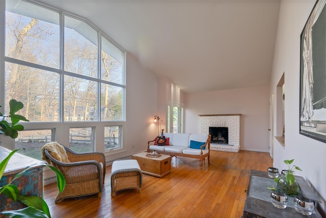 living room with hardwood / wood-style floors, a brick fireplace, and a high ceiling