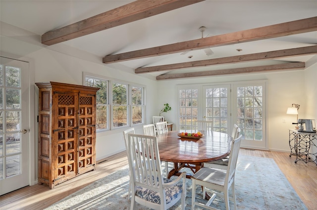 dining space featuring vaulted ceiling with beams and light hardwood / wood-style flooring