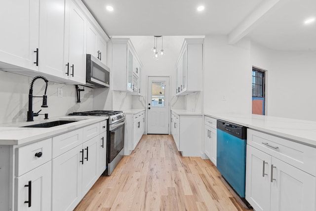 kitchen with beam ceiling, white cabinetry, sink, stainless steel appliances, and pendant lighting