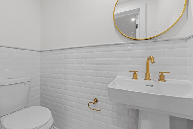 bathroom featuring toilet, sink, and tile walls