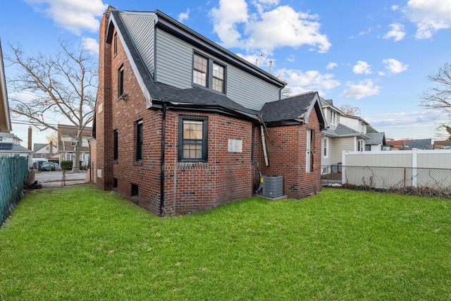 rear view of property with central air condition unit and a lawn