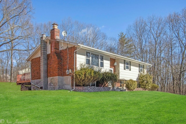 view of front of house featuring a front lawn, a chimney, and brick siding