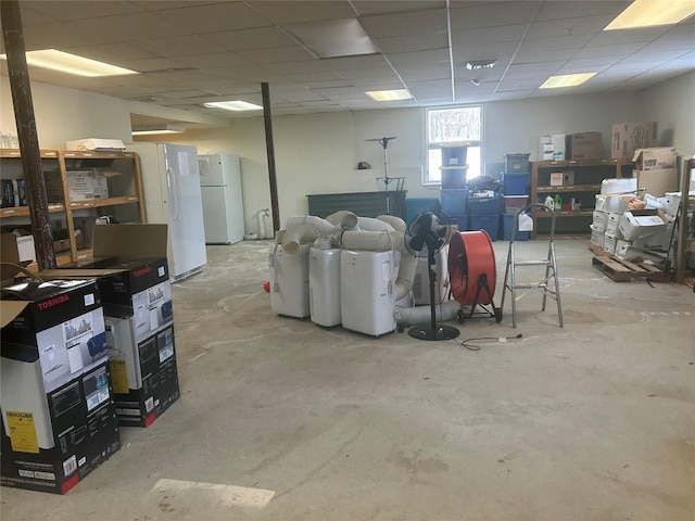 basement featuring white fridge and a drop ceiling