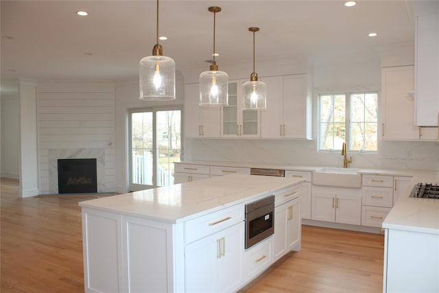 kitchen featuring white cabinets, built in microwave, a kitchen island, sink, and decorative light fixtures