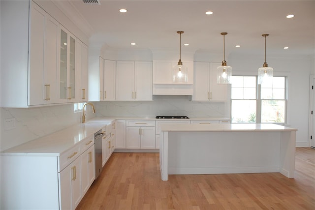 kitchen with pendant lighting, light hardwood / wood-style floors, a kitchen island, white cabinetry, and sink