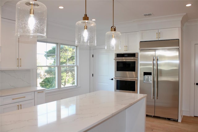 kitchen with light stone counters, appliances with stainless steel finishes, pendant lighting, and tasteful backsplash