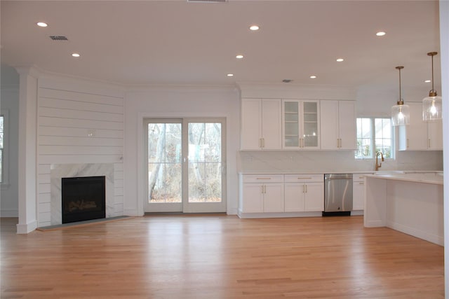 kitchen with a fireplace, dishwasher, a wealth of natural light, and white cabinetry