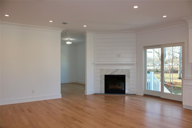 unfurnished living room featuring light hardwood / wood-style floors, crown molding, and a fireplace