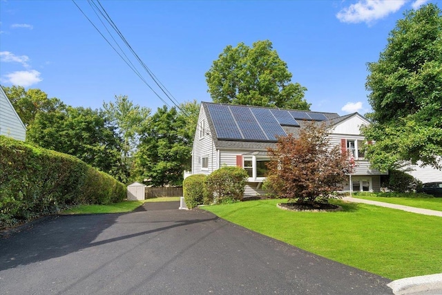 view of front of house with a front lawn, a storage unit, and solar panels