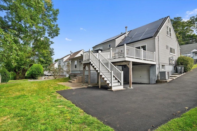 back of house featuring solar panels, central air condition unit, a yard, a garage, and a deck