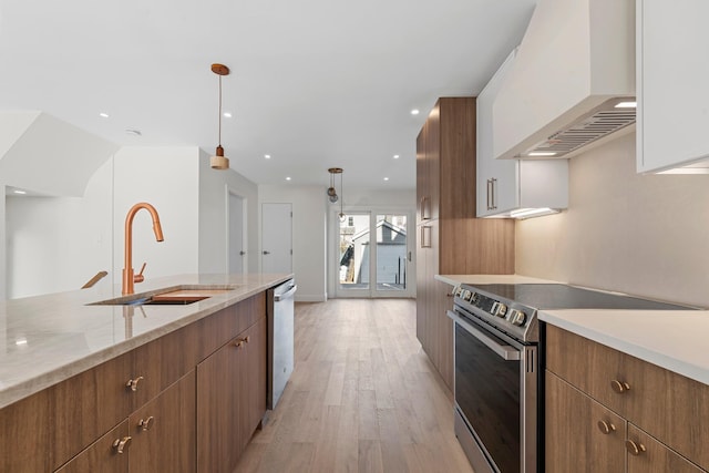 kitchen featuring premium range hood, white cabinets, sink, hanging light fixtures, and stainless steel appliances